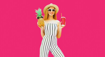 Summer portrait of beautiful woman drinking juice and holding pineapple wearing straw hat, striped...