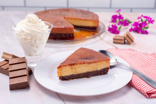 chocolate and flan dessert, inverted cake with chocolate sponge cake and milk flan with milk chantilly cream and chocolate bars on a marble countertop and decorated with natural flowers