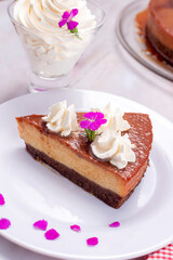 chocolate and flan dessert, inverted cake with chocolate sponge cake and milk flan with milk chantilly cream and chocolate bars on a marble countertop and decorated with natural flowers