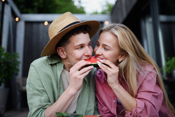 Cheerful young couple in love eating slice of watermelon together