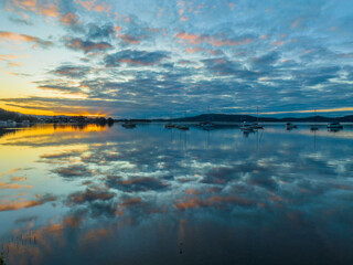 Aerial sunrise waterscape with boats, reflections and cloud filled sky