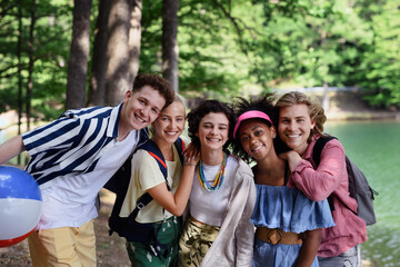 Group of young friends on camping trip near lake in summer.