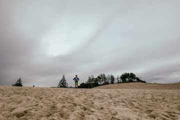 Kids climbing large sand dune near the beach at Forster, NSW Australia