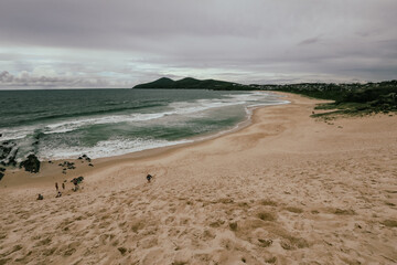 Kids climbing large sand dune near the beach at Forster, NSW Australia