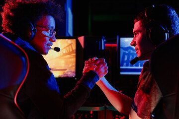 Side view of cyber sports team huddling in unity with video game screens in background