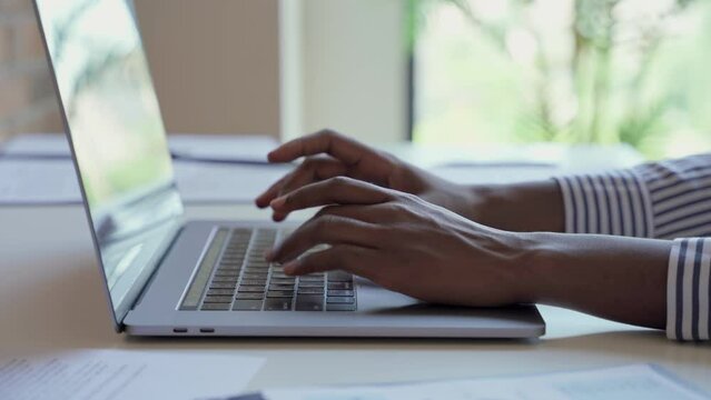 Young black female hands typing on pc keyboard. African business woman user using laptop computer working online, searching tech data in internet sitting at desk in home office. Close up view.