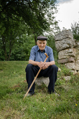 one man senior caucasian male pensioner old farmer standing alone outdoor in the field in backyard by ruined building foundation in summer day looking to the camera confident real people copy space
