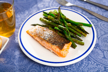 Just cooked portion of salmon steak with green asparagus served on table.