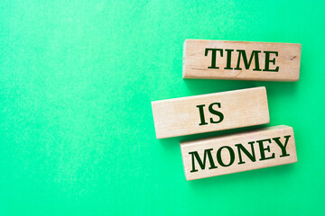 Time is money words on wooden blocks on green background.