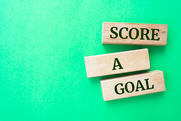 SCORE A GOAL words on wooden blocks on green background.