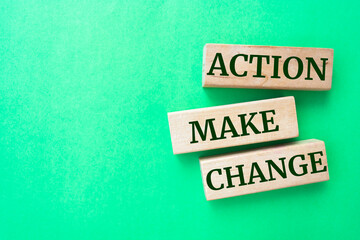 Action make change words on wooden blocks on green background.