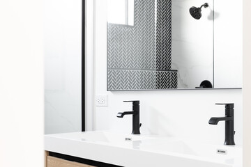 A beautifully renovated bathroom with a wood vanity cabinet, black marble herringbone tiles in the...