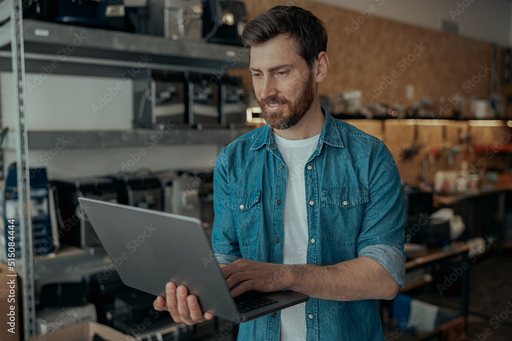 Wall mural handsome repairman in own workshop working on laptop