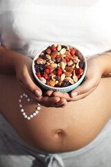 pregnant woman holding a bowl of dry fruit, top view