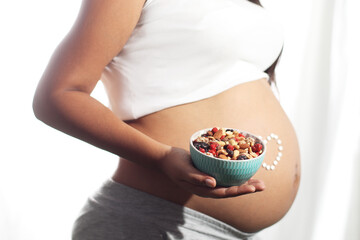 Pregnant woman belly holding dry fruits on hand