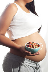 pregnant woman holding a bowl of dry fruit, portrait angle