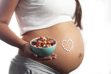 pregnant woman holding a bowl of dry fruit