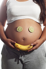 Pregnant woman latina fruit face on belly vertical
