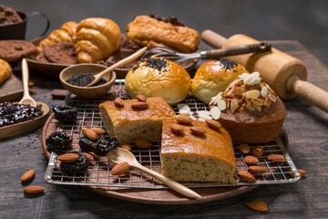 The bakery set consists of banana cake with almond topping, and bread sprinkled with black sesame seeds. Placed on a steel grid, Drake tone style.