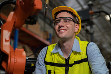 Engineer wearing helmet and hi visible vest working in factory welding robotic automation happy smiling with quality control pass 
