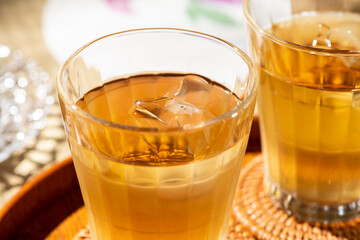 畳とお盆の背景にグラスにはいった冷たい麦茶と氷
