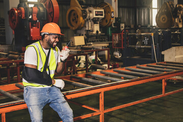 Male african american worker injured factory accident wears cast to work using walkie talkie...