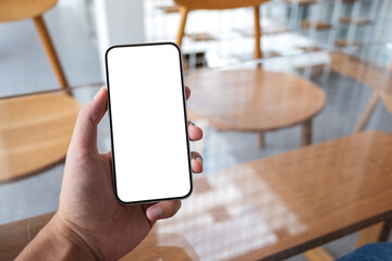 Mockup image of a man holding mobile phone with blank white screen in cafe