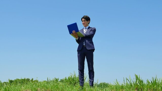 屋外でノートパソコンを使うビジネスマン