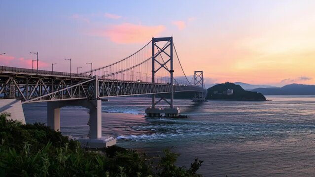 Timelapse of strong current flowing under suspension bridge at sunset