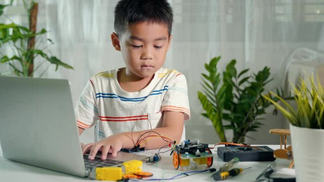 Asian kid boy learns coding and programming with laptop for Arduino robot car, Little child students typing code in computer with car toy, STEAM education AI technology course school learning