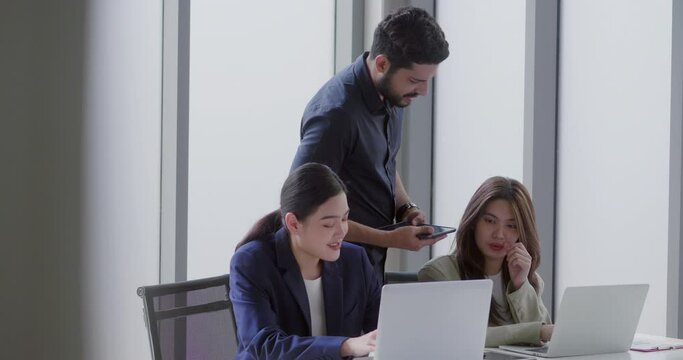 Businessman diligently and politely gives orders to his employees, a group of people working happily sitting on office desks. teamwork and technology concept