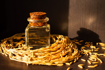 Rice bran oil in bottle glass with ears of rice grain wood background. top view. organic herbal...
