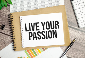 LIVE YOUR PASSION text on notepad and pen on wooden background
