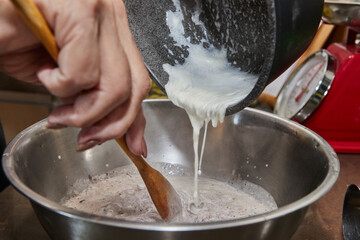 Chef pours whipped cream into a chocolate cake mix with pears and nuts. Step by step recipe