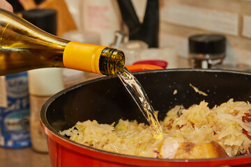 Pieces of smoked pork and sausage in saucepan are poured with white wine to make Alsatian sauerkraut - obrazy, fototapety, plakaty