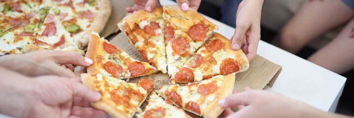 Hands of big company take piece of round shaped pizza