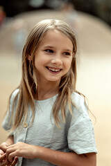 portrait of a beautiful 6-7-year-old girl with long blonde hair. A girl walks in the park in the summer. The face of a cute smiling girl