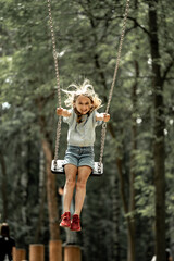 a girl walks in the park, swings on a swing