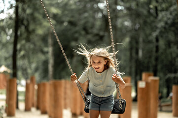 a girl walks in the park, swings on a swing