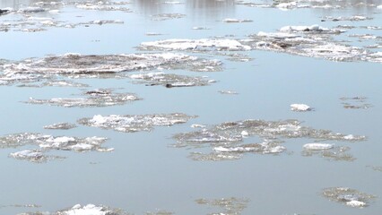 4k video, big and small dirty-white ice floes floating down a slow river. Spring, snow melting, ice...