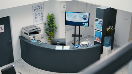 Nobody in empty waiting room lobby at hospital reception, checkup appointment reports on counter to help with healthcare system. Medical insurance at consultation in clinic waiting area.