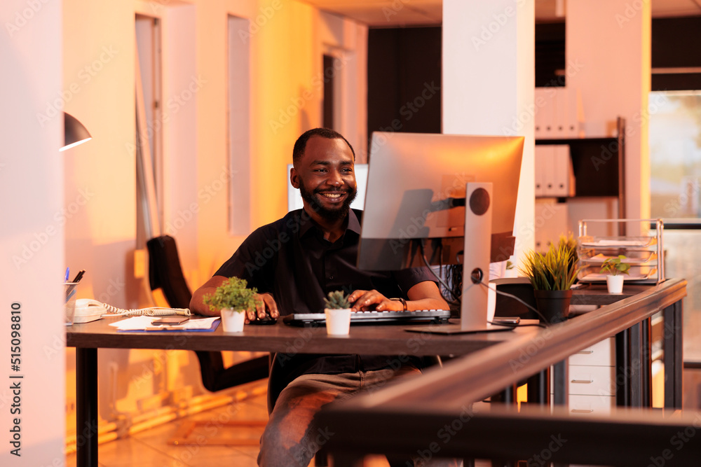 Poster smiling employee working on computer to do research on network, planning business project online. an