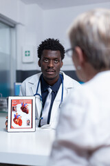 Cardiology doctor presenting heart problem and disease diagnostic to elderly cardiac patient....
