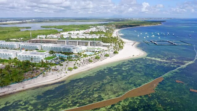 Boats moored at Cabeza de Toro beach with coastline and luxury beachfront resort in Dominican Republic. Aerial view