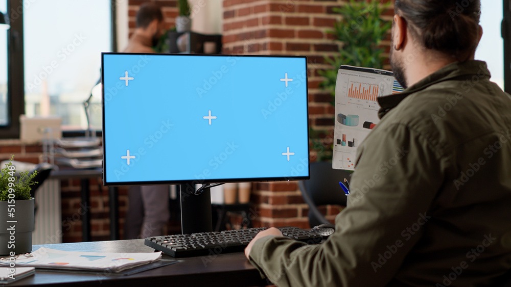 Poster startup employee looking at greenscreen template on monitor, working in business office with blank c