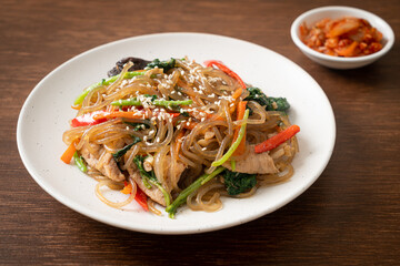 japchae or stir-fried Korean vermicelli noodles with vegetables and pork topped with white sesame