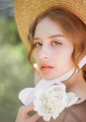 Close-up portrait of a cute blonde in a straw hat at sunset. Vintage tone..Soft blur background