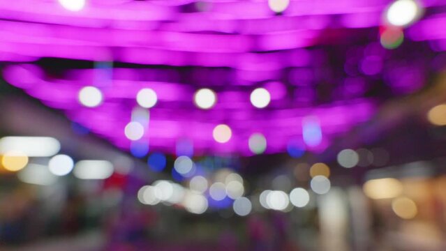 Blurred background in the night market, the light from the lamps creates zonal bokeh. by pink bulb