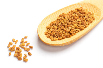 Fenugreek (Trigonella foenum-graecum) in bamboo spoon on white background isolated. Macro. Indian cuisine concept