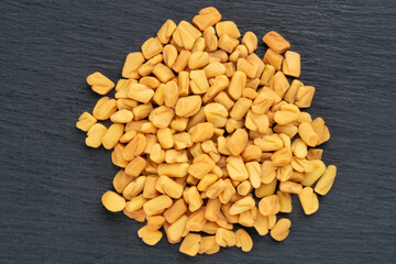 Bunch from fenugreek (Trigonella foenum-graecum) on black wooden background. Macro. Close up. Flat lay. Indian cuisine, ayurveda, naturopathy concept